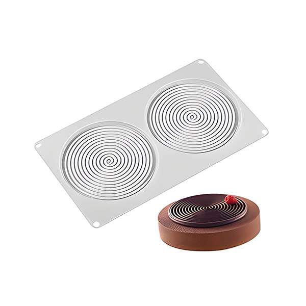 An image showing a spiral shape silicone mould and a finished dessert. The mould is rectangular with two circular cavities featuring spiral patterns. Next to the mould is a round dessert with a spiral design, topped with a cherry, and set on a brown base.