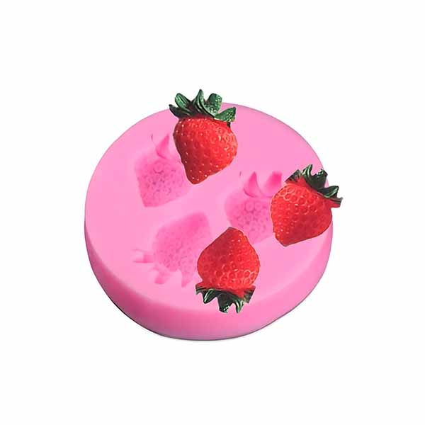 A pink silicone mold shaped like a round disc featuring three cavities in the form of strawberries. Three small artificial strawberries with green leaves are placed on top of the mold, enhancing its design.