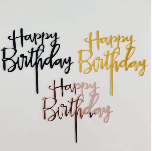 The image features three acrylic cake toppers, each with the phrase &quot;Happy Birthday&quot; in a stylish cursive font. The toppers are displayed on a white background. The first topper is black, the second is gold, and the third is a rose gold color. Each topper has a thin stem for easy placement on cakes.