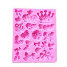The image features a pink silicone mould designed for creating decorative shapes. The mould contains various small designs, including bows, crowns, and hearts, arranged in a grid pattern. Each shape has a distinct outline, suitable for baking or crafting projects.