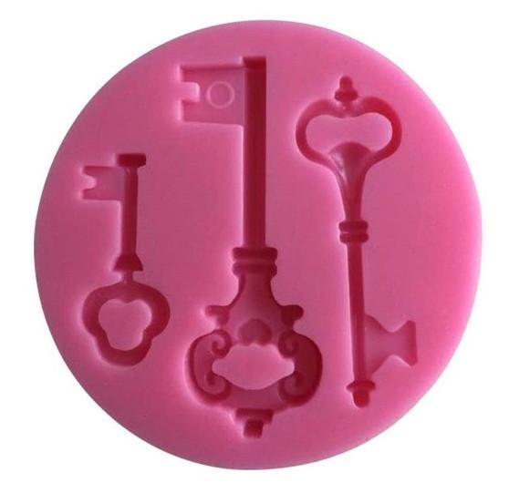 A round pink silicone mould featuring three vintage key designs in various shapes and sizes. The mould includes a small key on the left, a decorative key in the center, and a longer key on the right, all with intricate detailing.