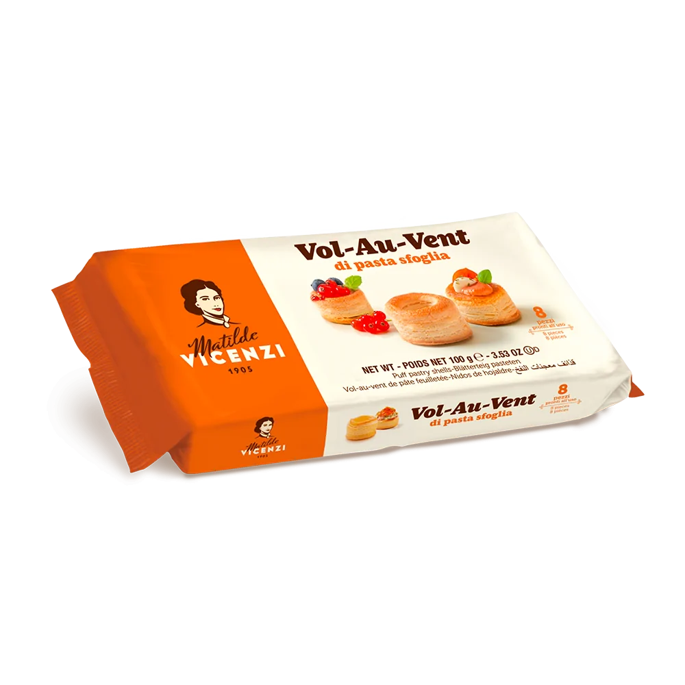 A package of Matilde Vicenzi Vol-Au-Vent puff pastry. The packaging features an orange and white design with the brand name &quot;Matilde Vicenzi&quot; at the top left and the product name &quot;Vol-Au-Vent di pasta sfoglia&quot; prominently displayed. The front of the package shows images of the puff pastry with garnishes, along with the product weight of 100g. The brand&