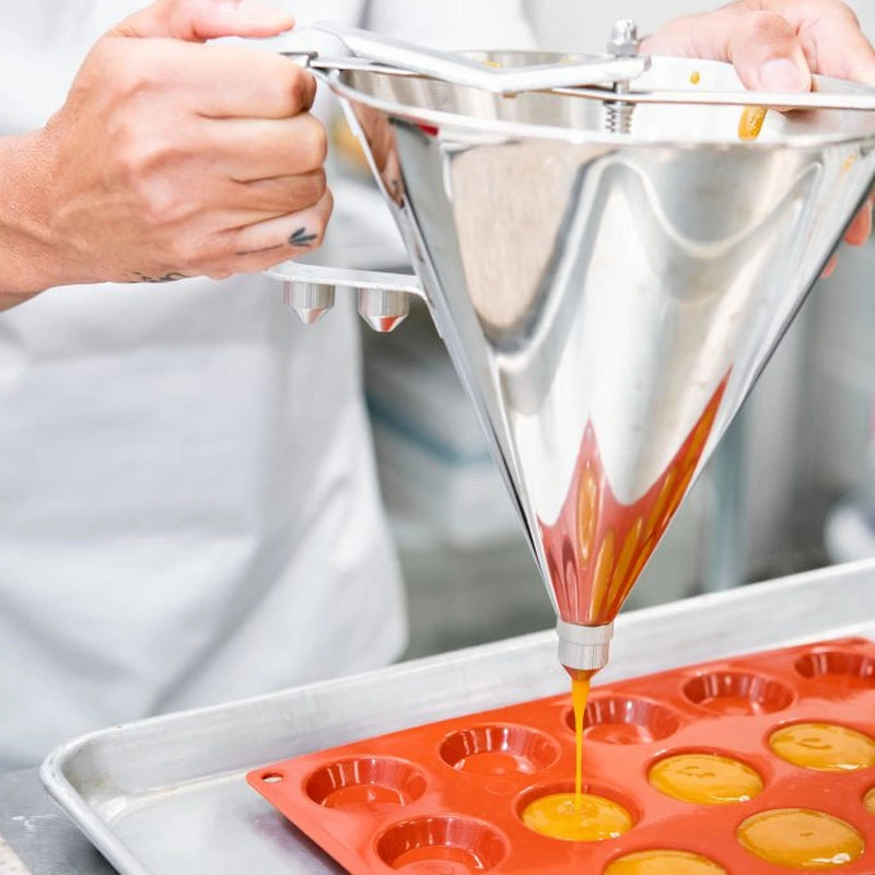 Someone is pouring orange batter into a muffin pan, preparing for muffin baking.