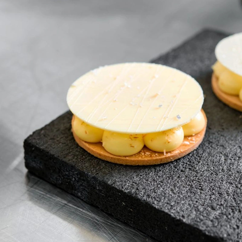 Two small white pastries arranged on a sleek black plate.