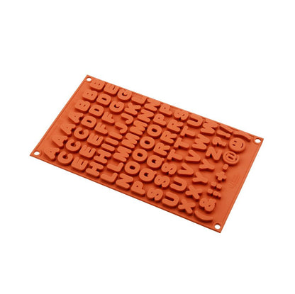 Red silicone mold with alphabet and numbers in reverse relief. The rectangular mold has rows of letters and symbols, conveying a playful tone.