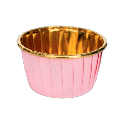 A pink cupcake liner with pleated sides and a shiny gold interior, set against a black background, creating an elegant and festive appearance.