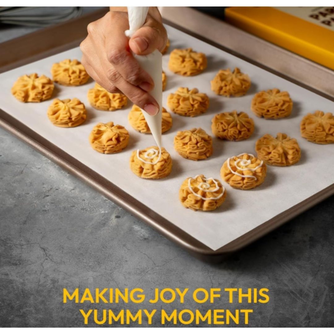 A hand delicately pipes icing onto orange cookies on a baking sheet, with "Making Joy of This Yummy Moment" text below, conveying warmth and creativity.
