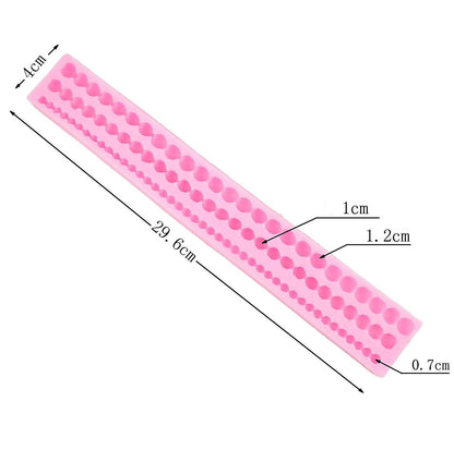 The image features a flexible pink silicone mold designed for creating pearl shapes. It measures approximately 29.6 cm in length and 4 cm in width. The mold consists of several rows of round cavities in different sizes, with marked dimensions of 0.7 cm, 1 cm, and 1.2 cm for some of the cavities. The design allows for the production of multiple pearl-like shapes at once.