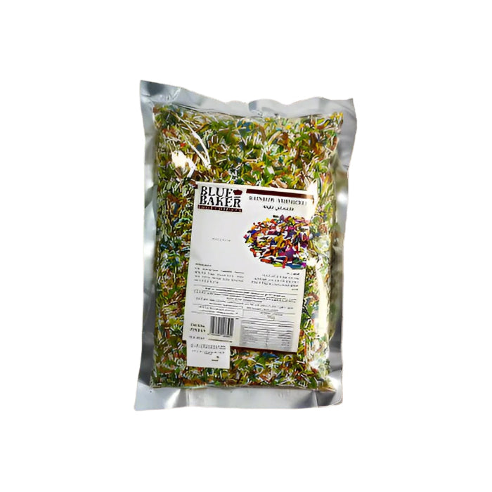 A 1 kg package of colored sprinkles labeled "Blue Baker" is placed on a wooden countertop. The transparent front of the package reveals a colorful mix of sprinkles. The back of the package displays product information and a barcode. 