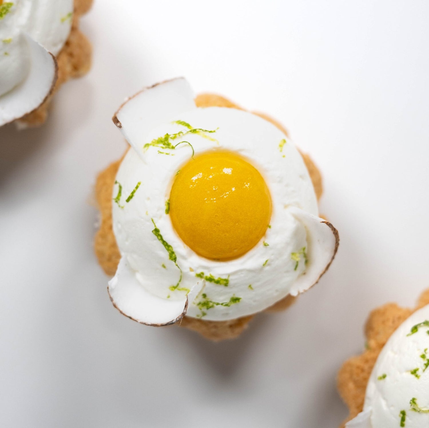 Three petite cakes, each adorned with an egg on top, displayed on a decorative platter.