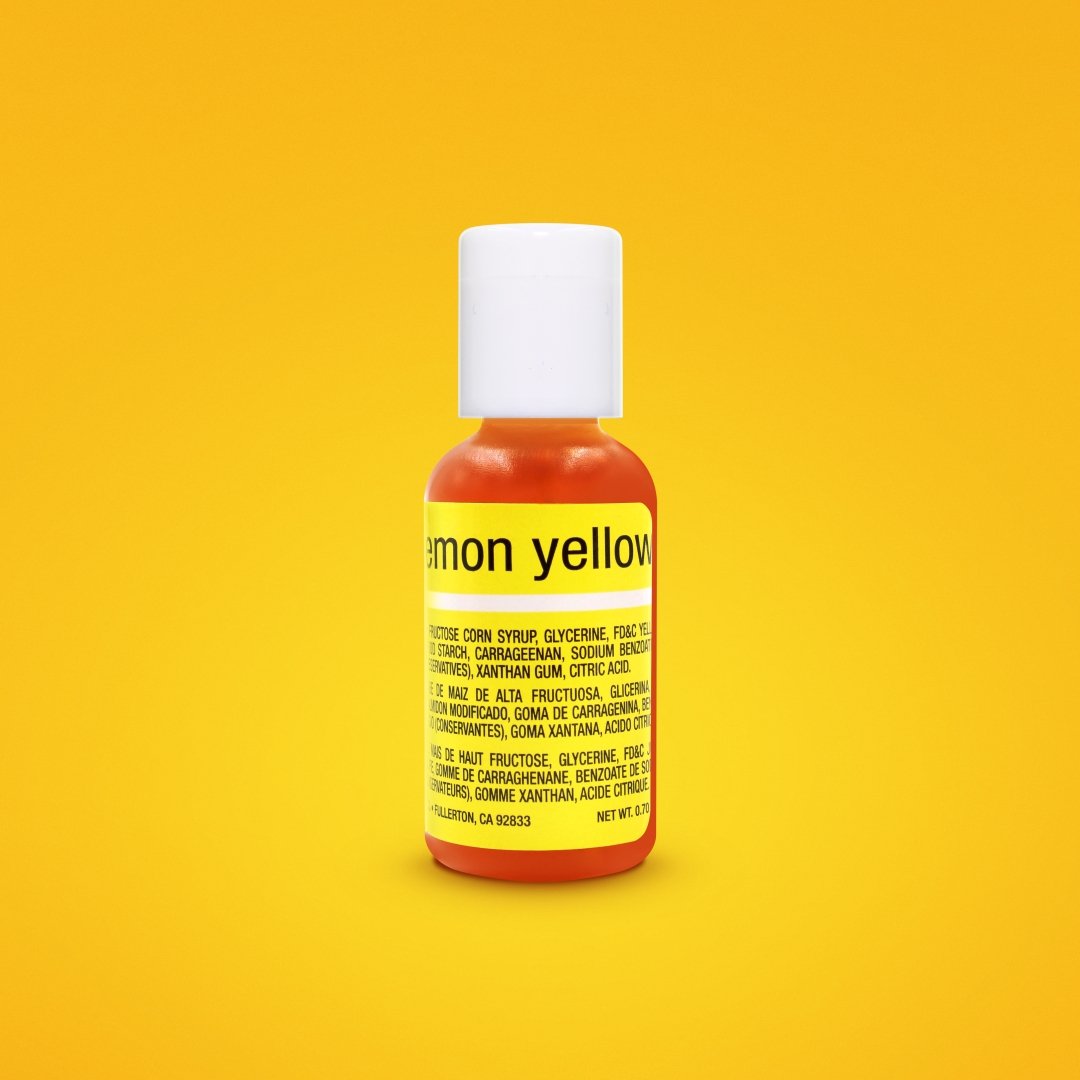 A small bottle of Chefmaster Liquid Gel Food Color labeled "Lemon Yellow" is prominently displayed against a vibrant yellow background. The bottle has a white cap and contains a bright yellow liquid. The label features ingredients and nutritional information, highlighted with yellow text. The total net weight is 0.7 oz (20 ml).