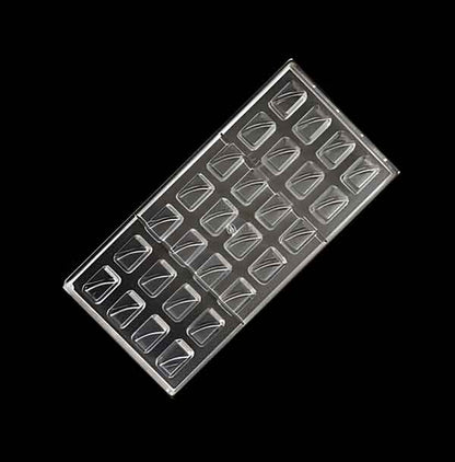 An overhead view of a chocolate mould featuring a rectangular design with multiple cavities, each shaped like a pyramid with a flat base and triangular sides. The mould is transparent, allowing light to pass through, and it contains 24 individual cavities arranged in four rows. The background is black, emphasizing the clear plastic of the mould.