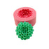 A pink silicone mold in the shape of a flower with a detailed green flower-shaped candle made from the mold placed in front.