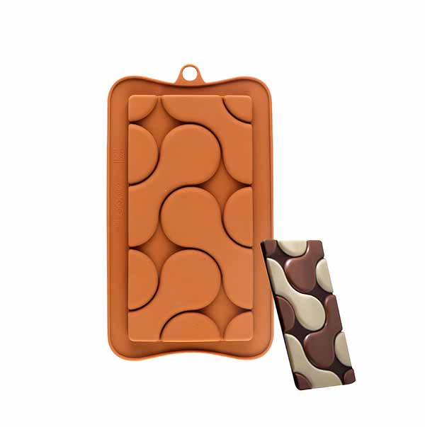 An orange silicone chocolate mold featuring circular and teardrop shapes is shown. To the right, there is a chocolate piece with a marbled design in dark brown, light brown, and cream colors, which was made from the mold. The mold has a top handle for easy removal.