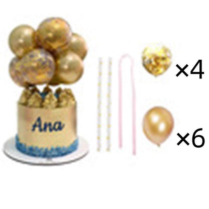 The image features a cake topped with a cluster of gold balloons, including one with confetti, along with decorative elements. The cake has a golden exterior with the name "Ana" written in blue and a blue border at the base. Surrounding the cake are additional party supplies: a set of four gold striped cake candles, a pink candle, and six gold balloons. The arrangement is designed for festive celebrations.