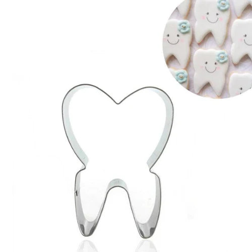 A tooth-shaped cookie cutter made of metal, featuring a heart-shaped top and a wider base resembling a tooth. In the corner, there is a circular inset showing decorated cookies shaped like teeth, with smiling faces and light blue flowers.