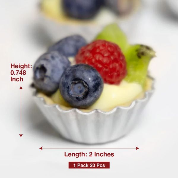 The image features a small tartlet filled with a creamy yellow filling, topped with fresh fruit including blueberries, a raspberry, and a slice of green fruit. The tartlet is presented in a silver, fluted aluminum cup. Text in the image indicates the dimensions, with a height of 0.748 inches and a length of 2 inches, and notes that the product comes in a pack of 20 pieces.