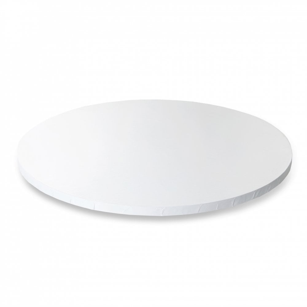 A thick, round white cake drum is displayed on a light background. The cake drum has a smooth surface and a slightly raised edge. It is designed for supporting cakes and pastries.