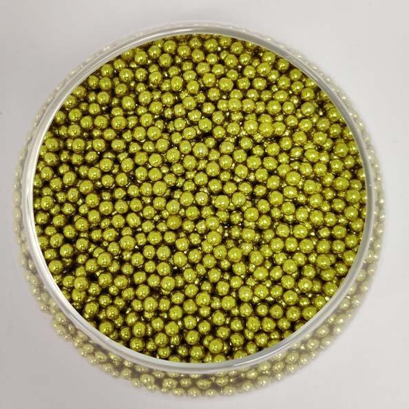 A clear plastic container filled with small, round, shiny gold sugar pearls. The pearls are densely packed, creating a uniform surface. The container has a smooth edge and sits on a white background.