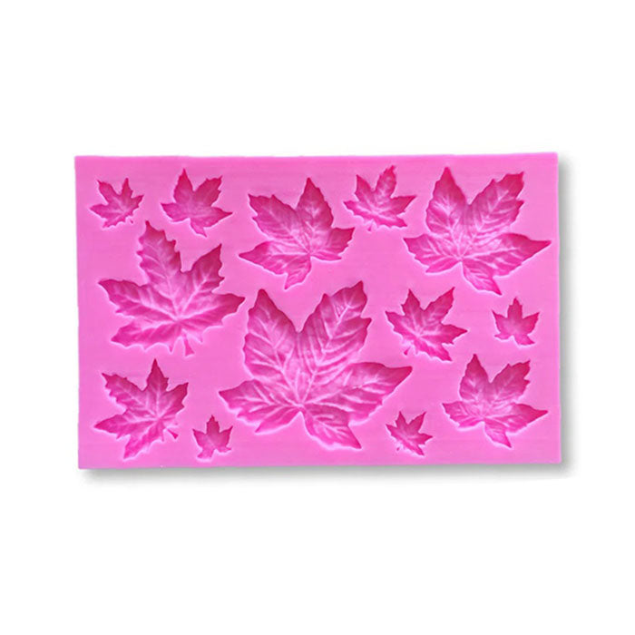 A pink silicone mould featuring various sizes and shapes of maple leaf designs. The mould includes several leaf impressions, ranging from small to large, arranged in a rectangular form. The intricate details of the leaves are visible, showcasing their unique outlines and textures.