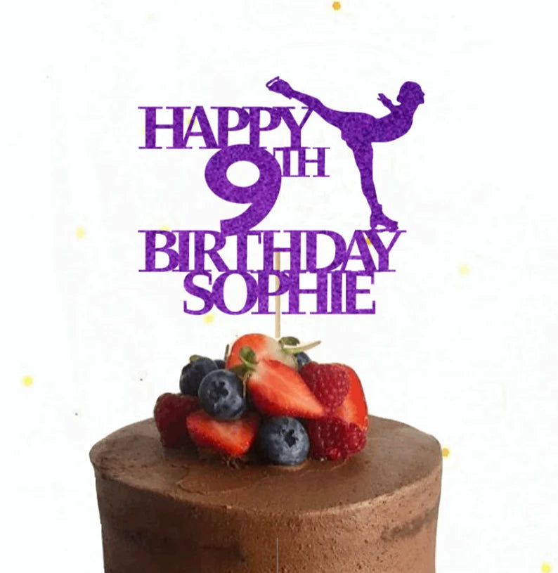 A chocolate cake topped with fresh strawberries and blueberries, featuring a purple glitter card cake topper that reads &quot;HAPPY 9TH BIRTHDAY SOPHIE&quot; along with an image of an ice skater in a dynamic pose. The background is light, with some decorative elements, enhancing the festive appearance of the cake.