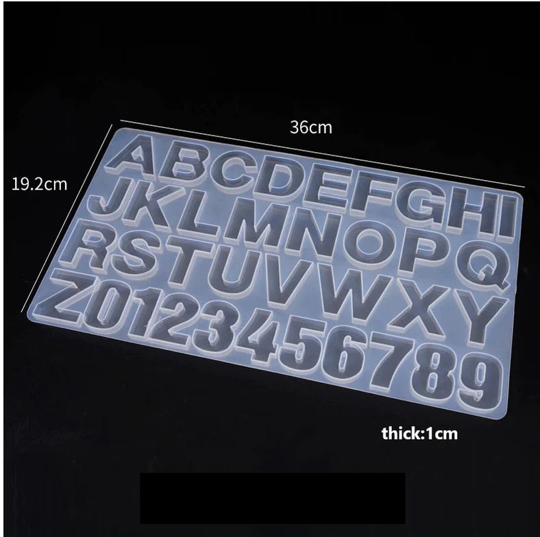 A silicone mold featuring large letters from A to Z and numbers 0 to 9, measuring 36 cm by 19.2 cm and 1 cm thick. The mold is transparent and is displayed against a dark background.