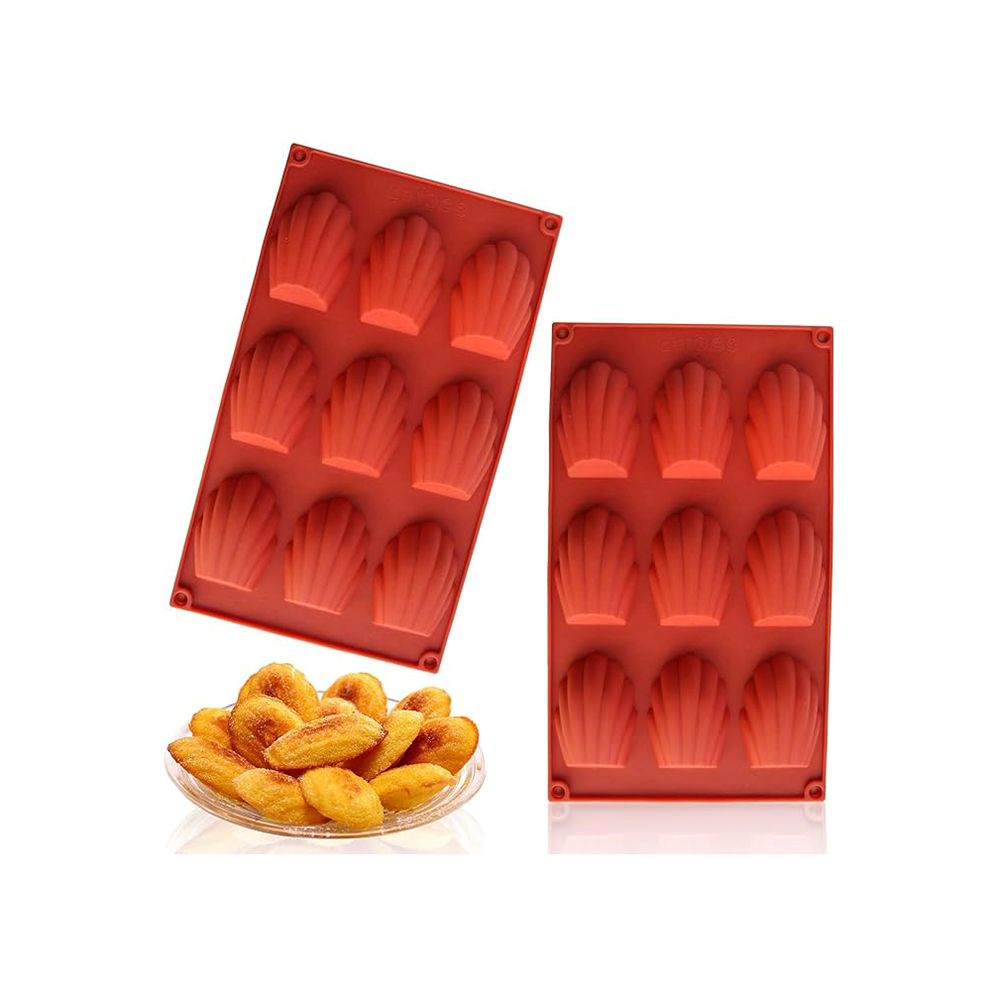Red silicone madeleine molds are shown alongside a plate of golden-brown madeleines. The scene conveys a fresh, homemade baking vibe.