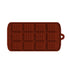 A rectangular mini silicone mold designed for making chocolate bars, featuring 12 square cavities arranged in three rows. The mold is a rich brown color, resembling chocolate, and has a small handle with a hole for easy hanging. Each cavity has a textured surface to mimic the appearance of a chocolate bar.