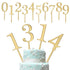 The image features a set of golden cake toppers arranged at the top and on a decorated cake. The top section displays numerical toppers from 0 to 9, while the bottom section showcases the numerals 1, 3, and 4 inserted into a light blue, multi-tiered cake adorned with white floral decorations and intricate designs. The cake has a smooth finish, and the cake toppers are prominently featured, adding a celebratory touch.