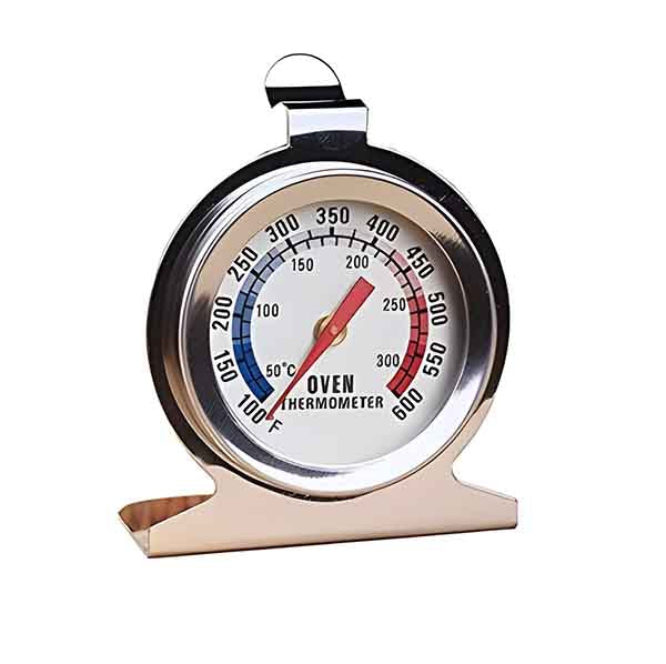 A round metal oven thermometer with a white face displaying temperature in both Celsius and Fahrenheit. The thermometer has a red needle indicating the current temperature, marked with ranges from 100°F to 600°F and 50°C to 300°C. It features a sturdy metal stand for stability.