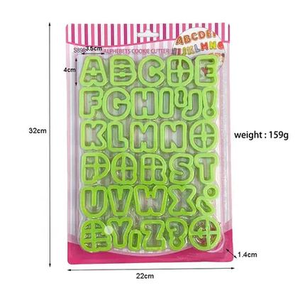 A packaging of green plastic alphabet cookie cutters, featuring letters A to Z, plus symbols such as an exclamation mark and a question mark. The cutters are arranged in a grid on the packaging, which is transparent with a colorful bordered top and includes pink accents. The dimensions listed on the package are 32 cm in height, 22 cm in width, and 1.4 cm in depth, with a weight of 159 grams.