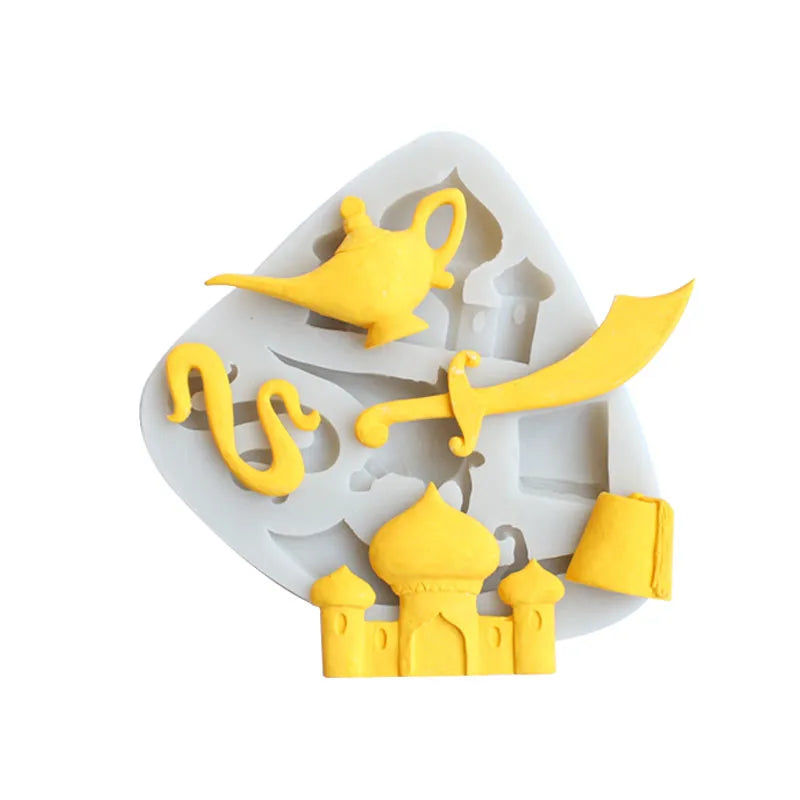 The image features a silicone mold shaped like a white and gray tray, with several yellow figures molded into it. The designs include a magic lamp, a curved sword, a snake, and a palace or castle with dome-shaped tops. The items are intricately detailed and share a thematic resemblance to a story inspired by &