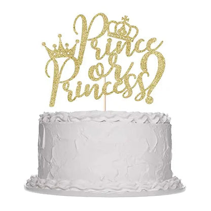 A simple white cake with a textured frosting, topped with a gold glittery cake topper that reads "Prince or Princess!" in an elegant script font, adorned with crowns.