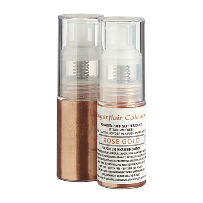 The image features two transparent spray bottles of Sugarflair Edible Glitter Dust in Rose Gold. The bottle on the front has a bronze base with a white spray nozzle and a label that reads &quot;Sugarflair Colours - Powder Puff Glitter Dust (Titanium Free) - Rose Gold.&quot; The label includes usage instructions, indicating it is suitable for food decoration. The background is plain, emphasizing the product&