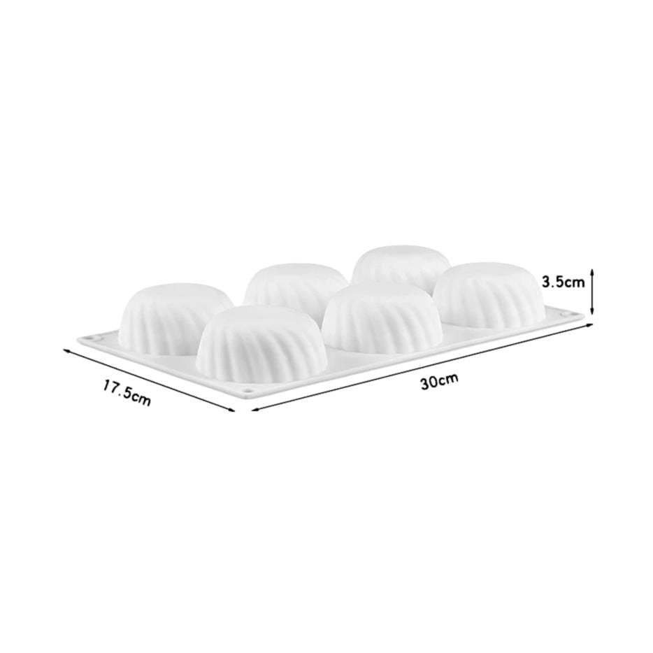 A tray holds six white cupcakes, each topped with a swirl of frosting, arranged neatly for display.