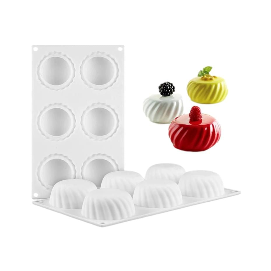 Six cupcake molds in various colors and a round cake pan displayed together on a neutral surface.