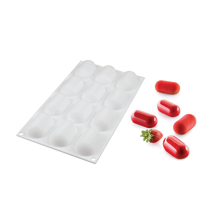 A white silicone mold featuring 12 mini rounded oval cavities is shown. The mold is accompanied by several red, oval-shaped confections and a small green strawberry, demonstrating the mold&