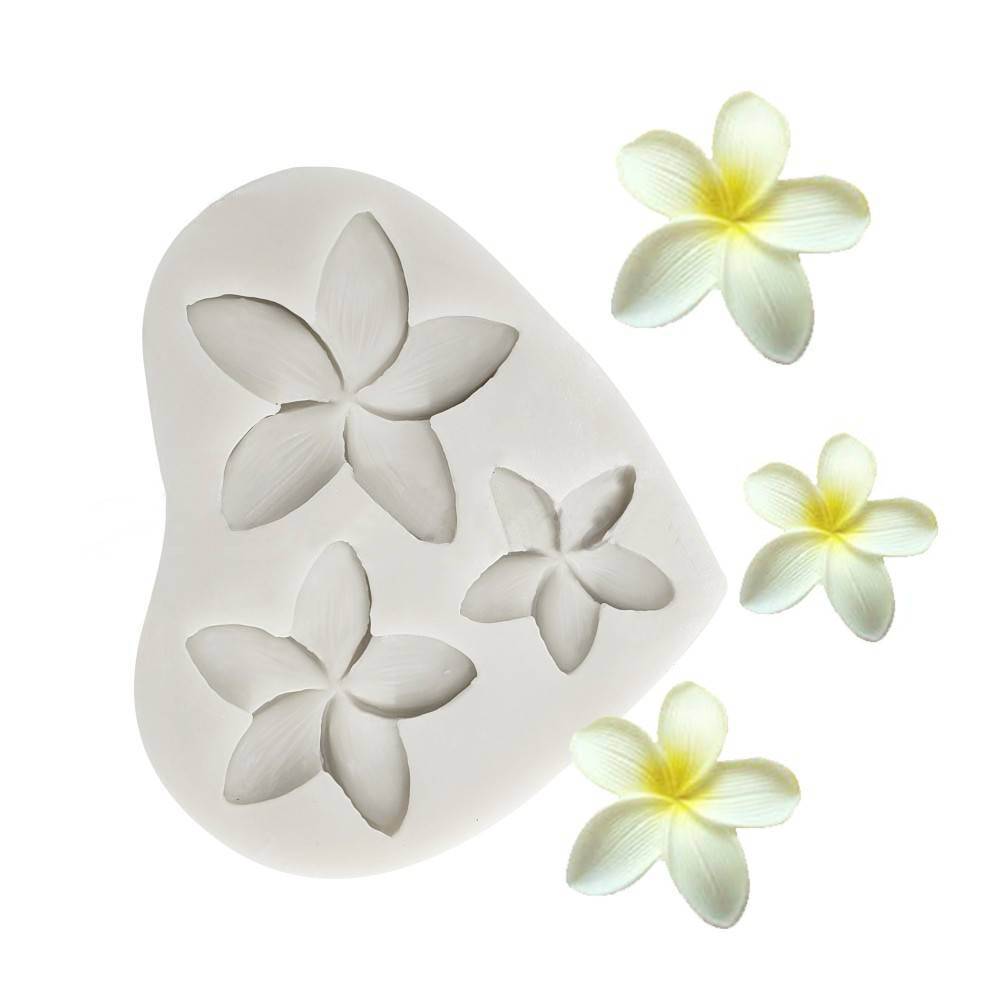 A white silicone mould shaped like a heart, featuring three plumeria flower cavities of varying sizes. Surrounding the mould are several lifelike plumeria flowers, displaying white petals with yellow centers. The background is plain and bright, highlighting the mould and flowers.