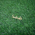 A wooden cake topper that reads "Soulmates" in an elegant cursive font, placed on a textured green grass background.