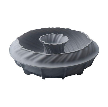 A gray silicone bundt cake mold with intricate, swirling ridges and a central tube. The mold has a soft, flexible texture and a modern design.