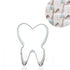 A tooth-shaped cookie cutter made of metal, featuring a heart-shaped top and a wider base resembling a tooth. In the corner, there is a circular inset showing decorated cookies shaped like teeth, with smiling faces and light blue flowers.