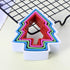 A set of five cookie cutters shaped like trees, stacked together. The cookie cutters are made of colorful plastic, with the outer layer being white, followed by green, pink, red, and blue layers in a nested arrangement. They are placed on a light-colored surface, with a wire cooling rack partially visible in the background.