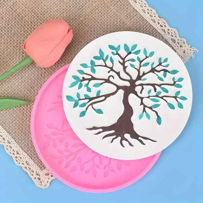 A close-up of a pink silicone tree-design mold with a completed fondant decoration of a tree, including green leaves and brown branches, resting on a burlap mat with a decorative tulip.