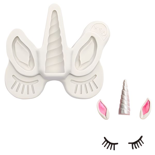 An image of a white silicone mold shaped like a unicorn head, featuring ears, a twisted horn, and eyelashes. The mold contains spaces for creating a unicorn horn, two ears, and eyelashes. Next to the mold are three finished pieces: a pink and white horn, two pink-tipped ears, and a pair of black eyelashes.