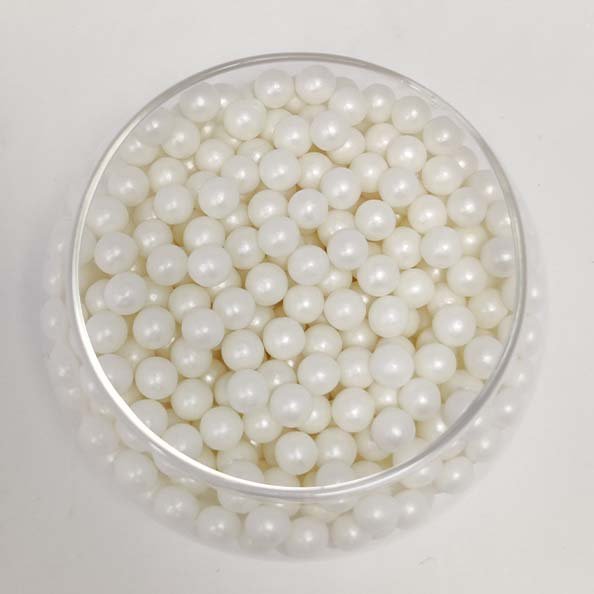 A clear container filled with small, round, glossy white sugar pearls. The pearls are uniform in size and have a shiny, pearl-like appearance. The background is neutral, allowing the focus to remain on the container and its contents.