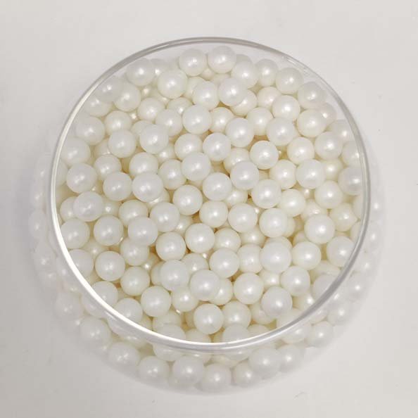 A clear container filled with small, round, glossy white sugar pearls. The pearls are uniform in size and have a shiny, pearl-like appearance. The background is neutral, allowing the focus to remain on the container and its contents.